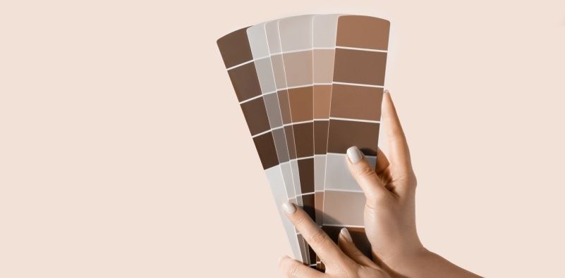 A person holding colour charts with different Mocha Mousse tones
