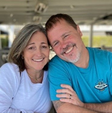 A man and a woman are posing for a picture and smiling for the camera