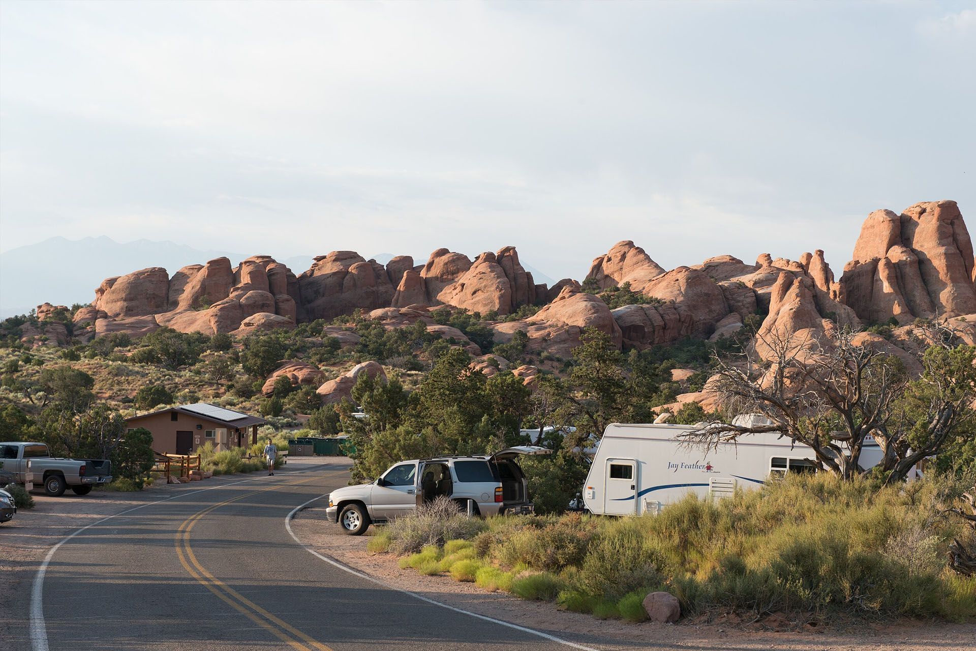 Devil's Garden Campground with RVs, cars, and buildings nestled near red rock formations.