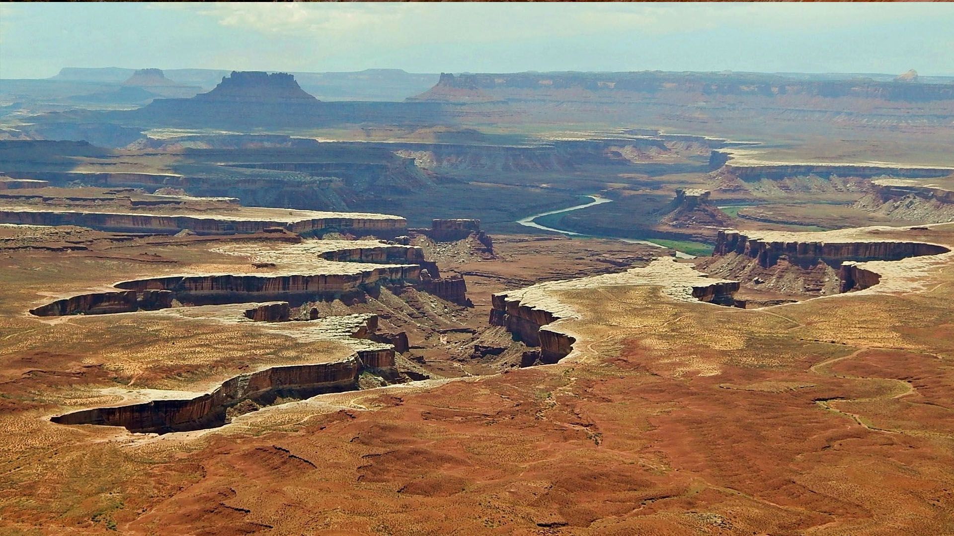 Red rock canyons and mesas stretch to the horizon; a river winds through the landscape.