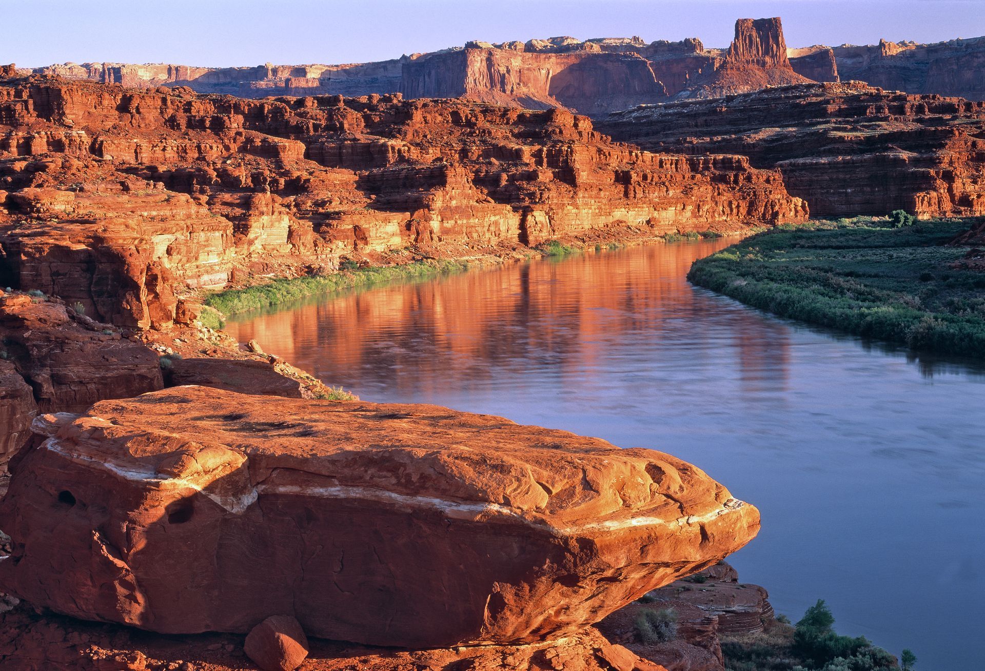 Red rock canyon landscape with a river winding through, bathed in warm light.
