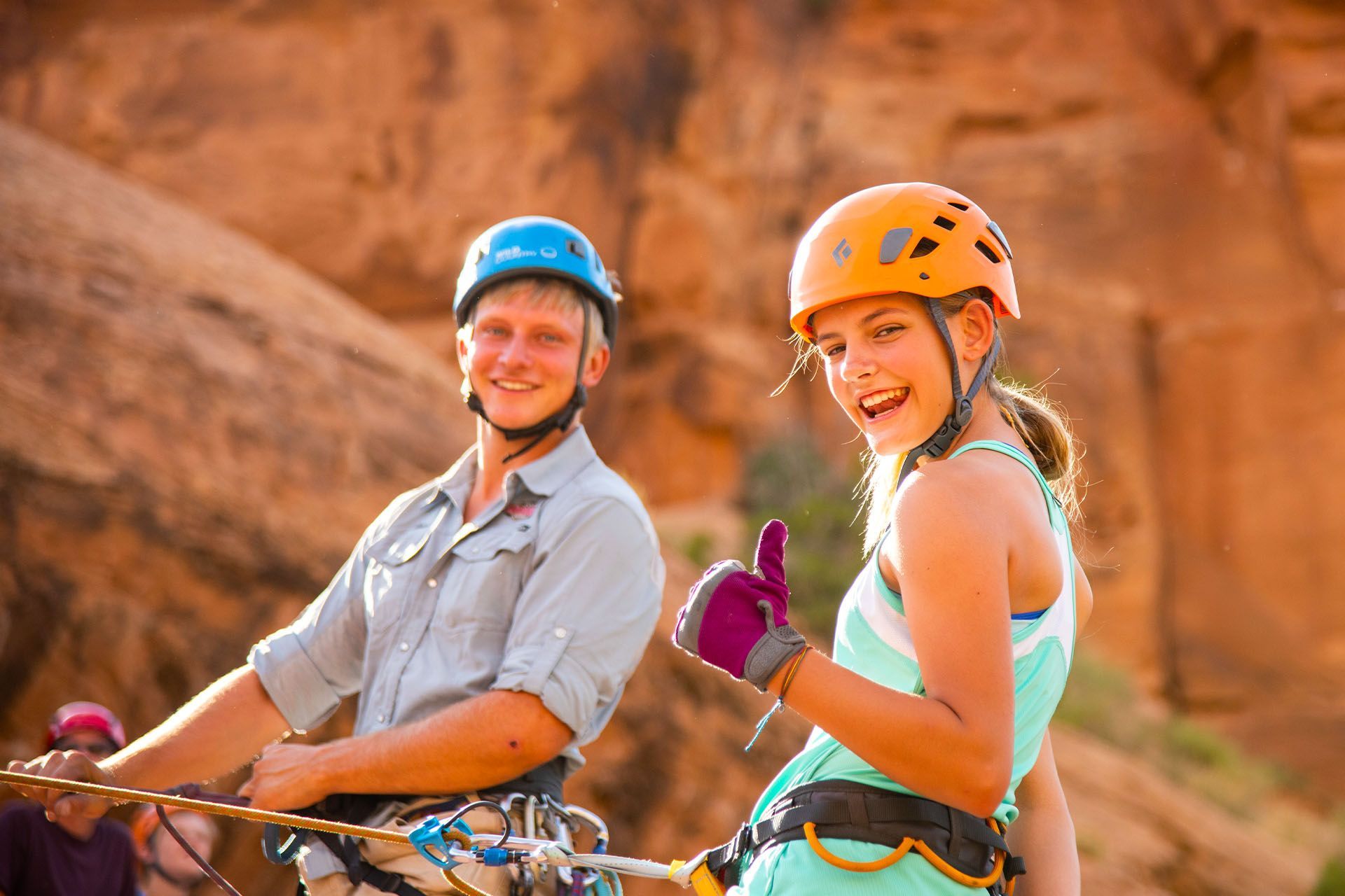 A smiling girl rock climbing for her first time in Moab, Utah.