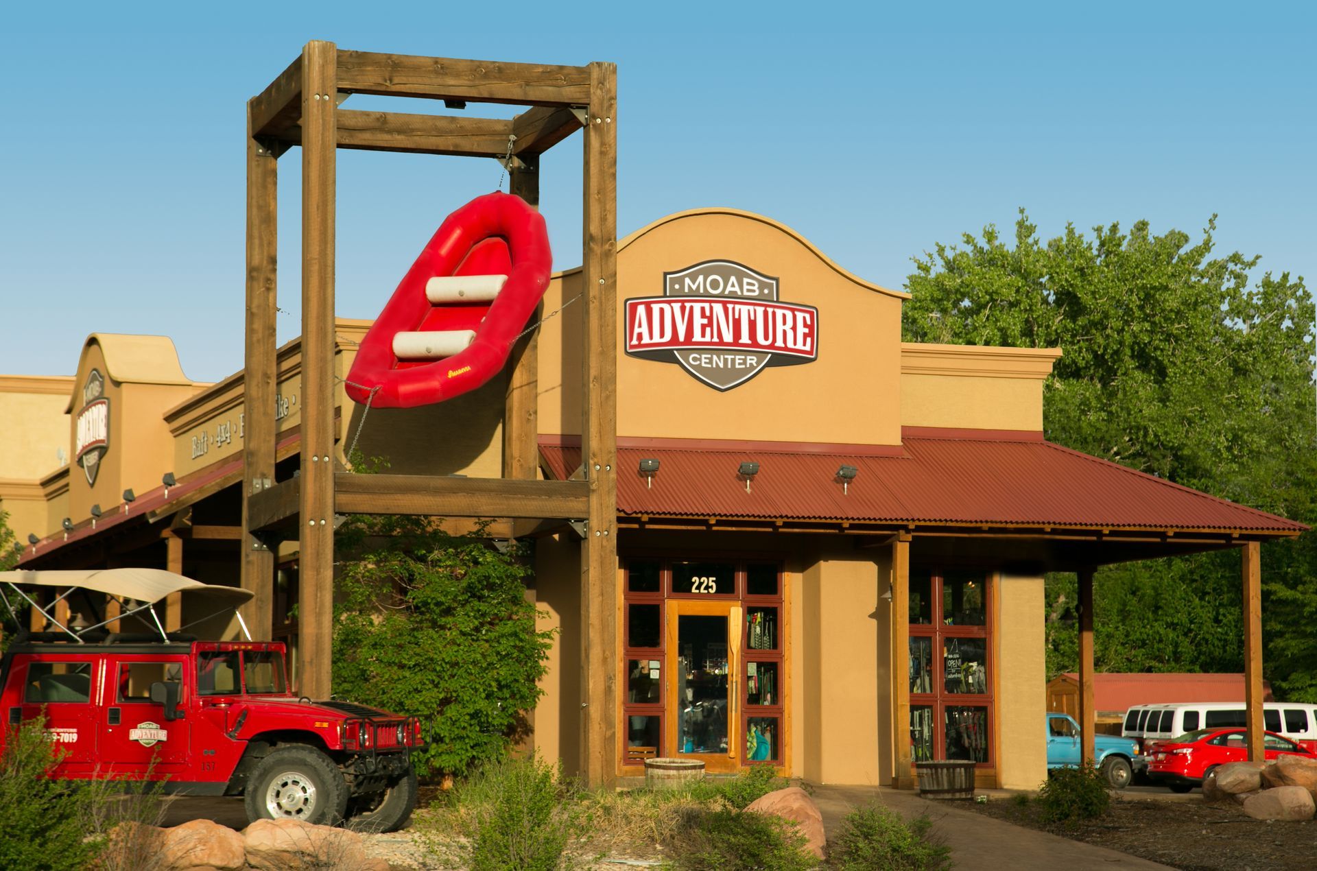Raft hanging on wooden structure in front of Moab Adventure Center building.
