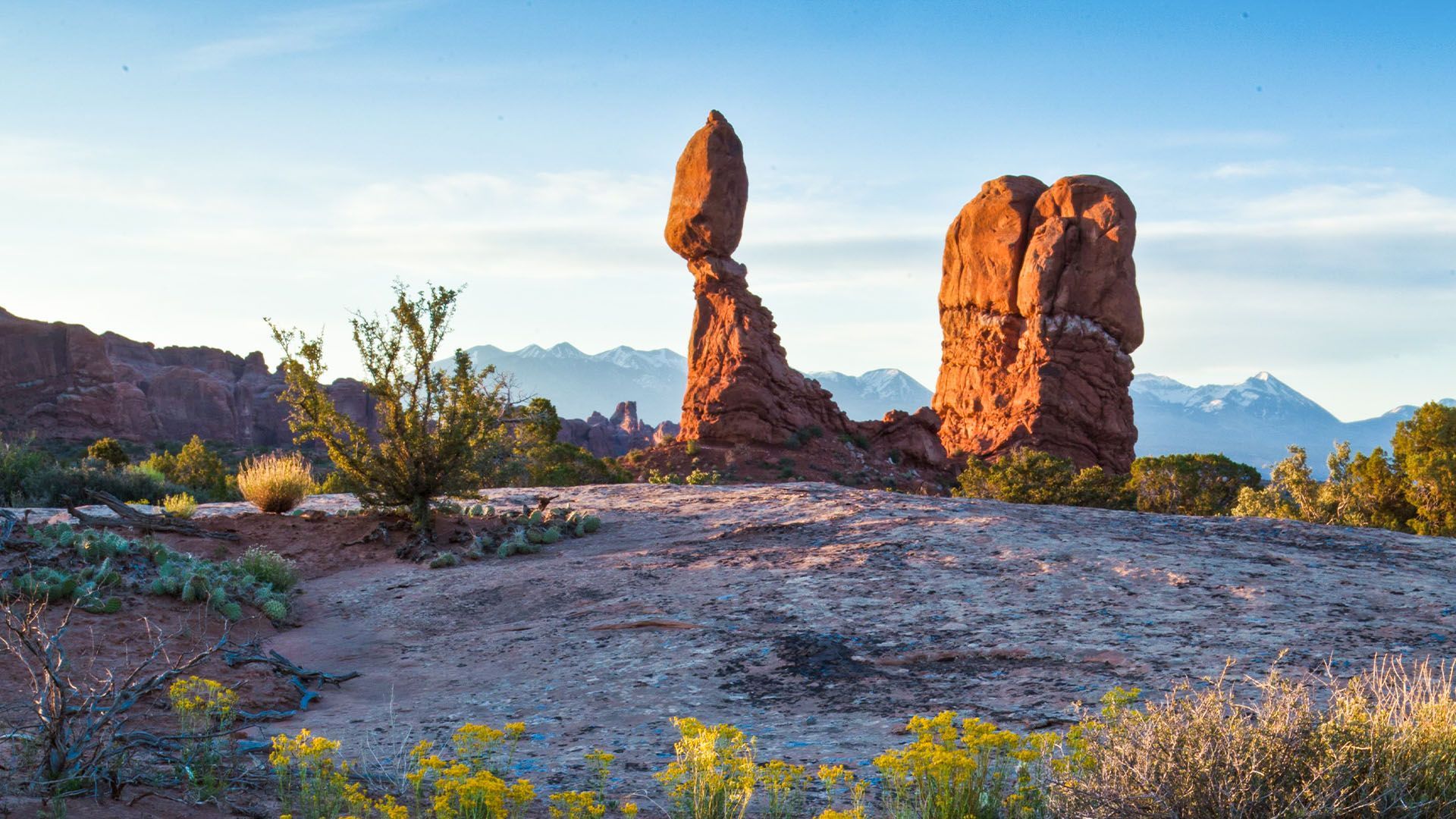 Balanced Rock in Arches National Park, Utah, with mountains in background.