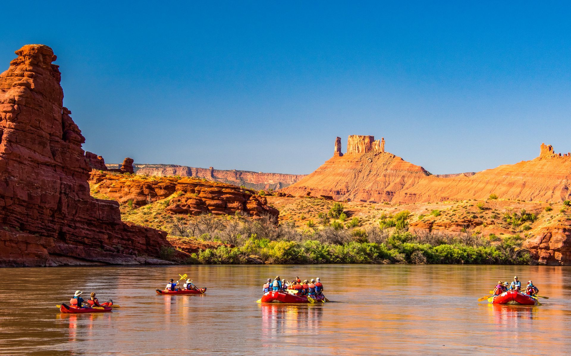 A business group floats down the Colorado River in 2 paddle rafts and 2 inflatable kayaks.
