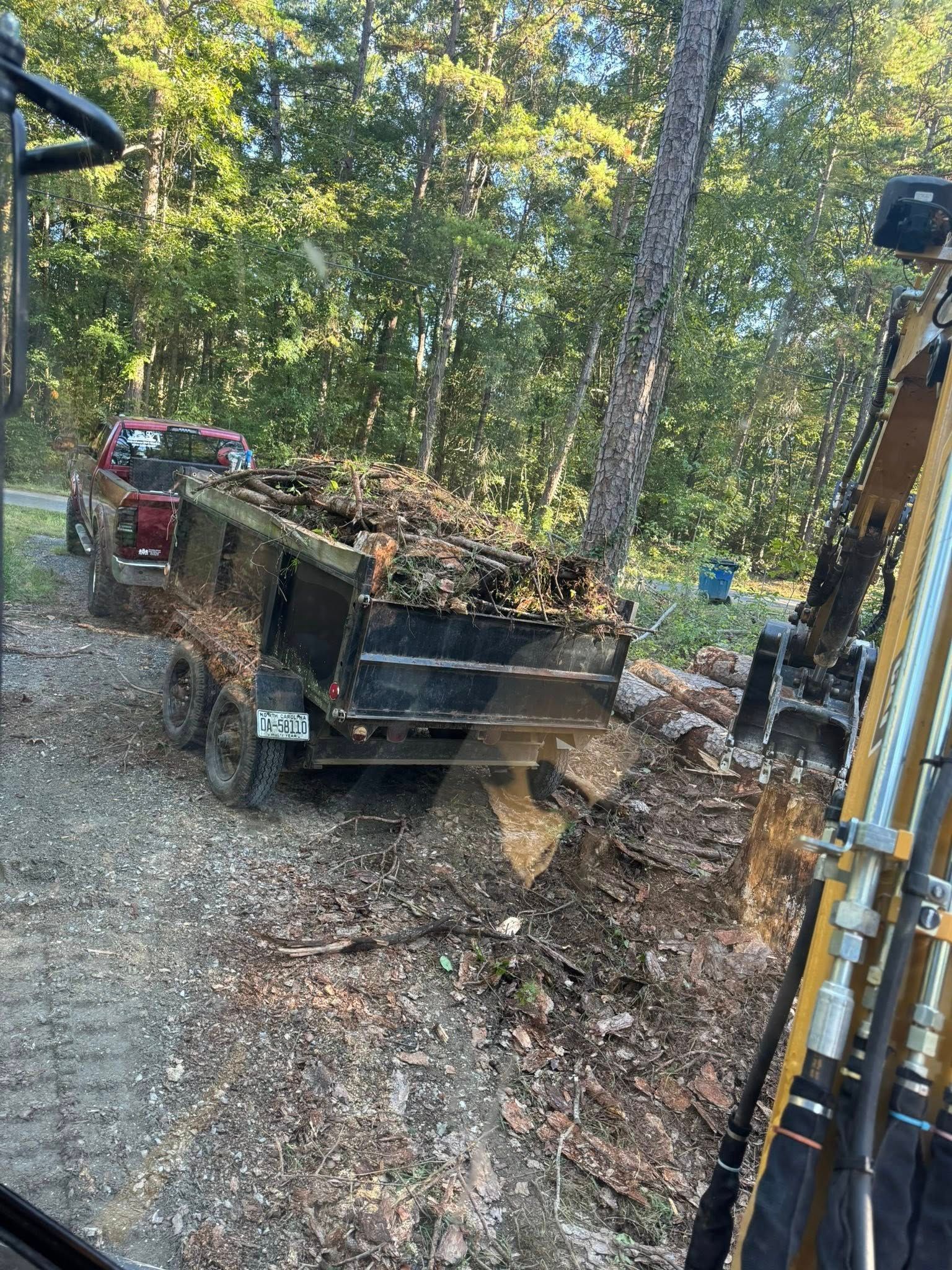 Dump truck loaded with leaves on a gravel driveway in a wooded area