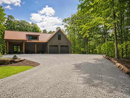 Open-sided metal barn with tractors and farm equipment on a concrete floor