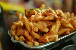 Close-up of saucy fried chicken pieces piled in a black serving dish