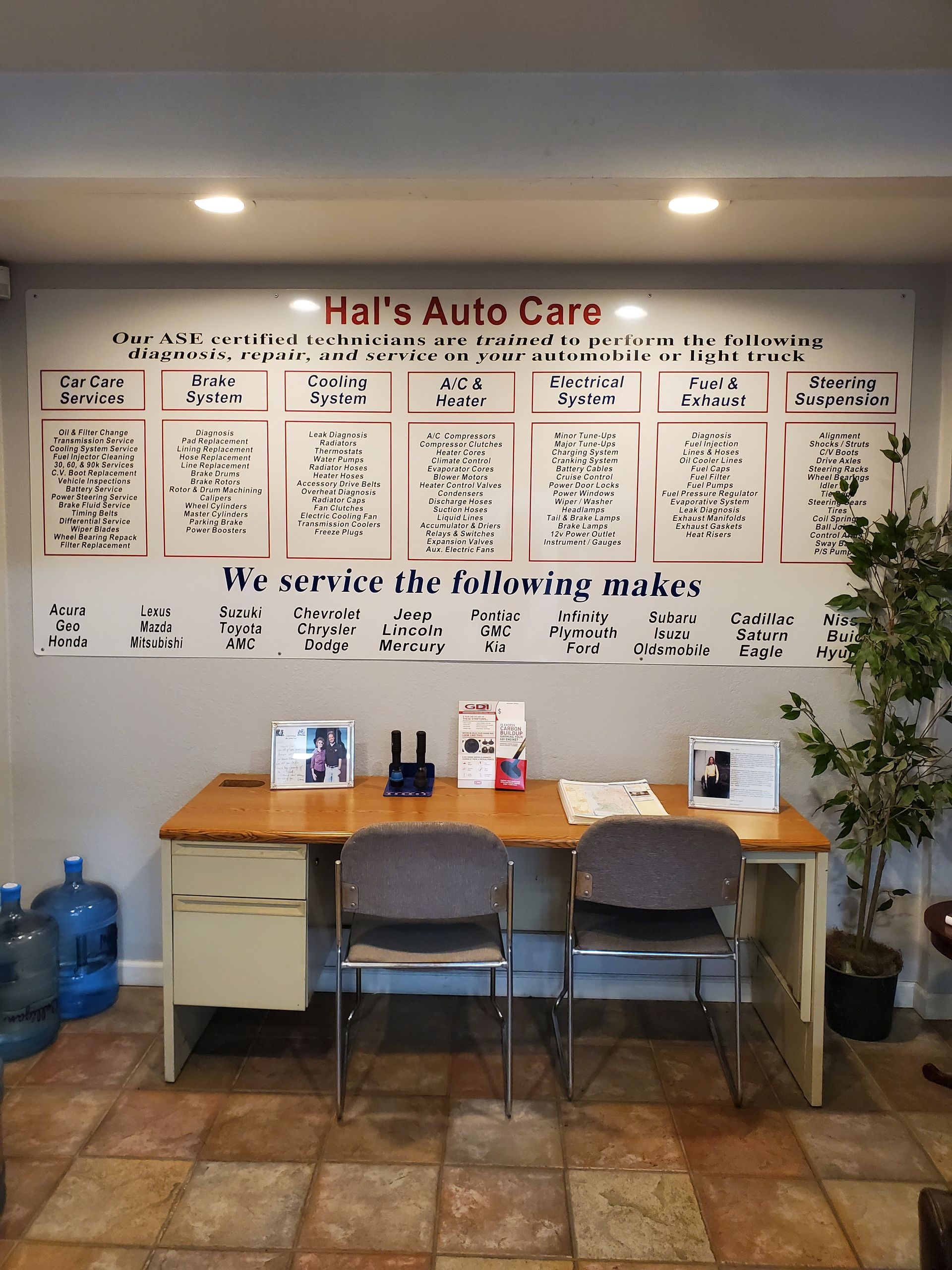 Hall's Auto Care waiting area with a desk, two chairs, water bottles, and a service menu. | Hal's Auto Care