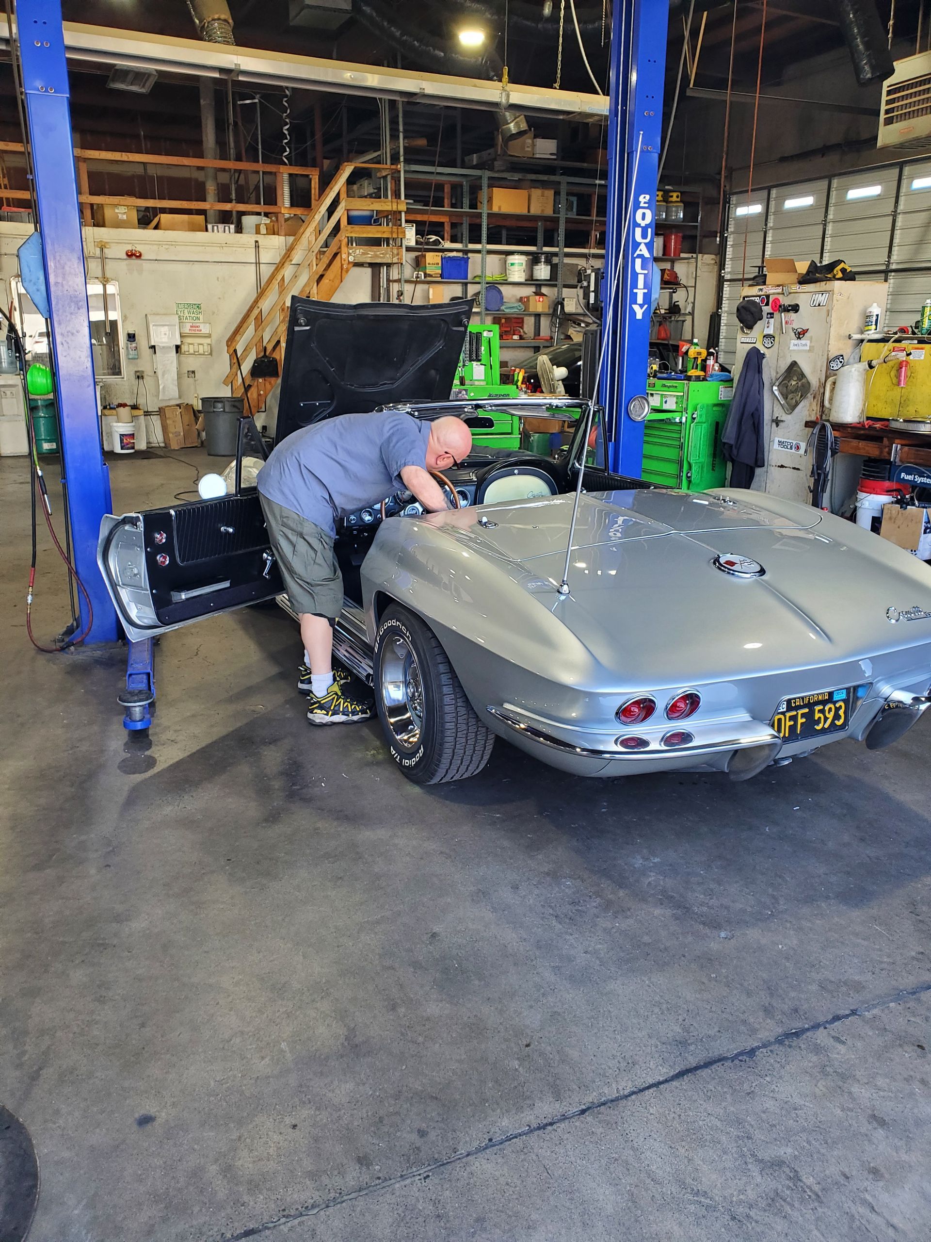 Mechanic working on a silver vintage Corvette convertible inside a garage. | Hal's Auto Care