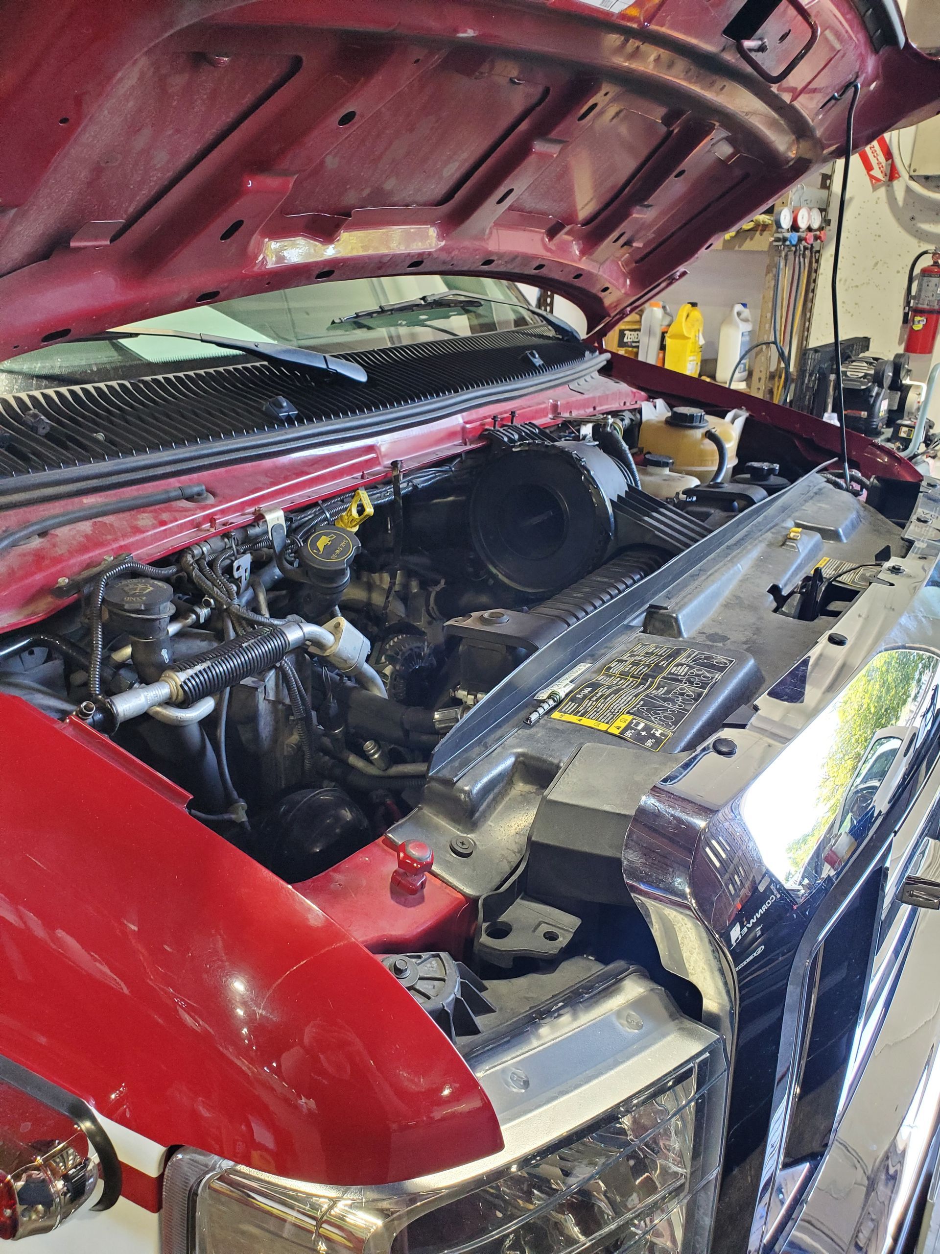 Red pickup truck with hood open, revealing engine compartment, in a garage setting. | Hal's Auto Care