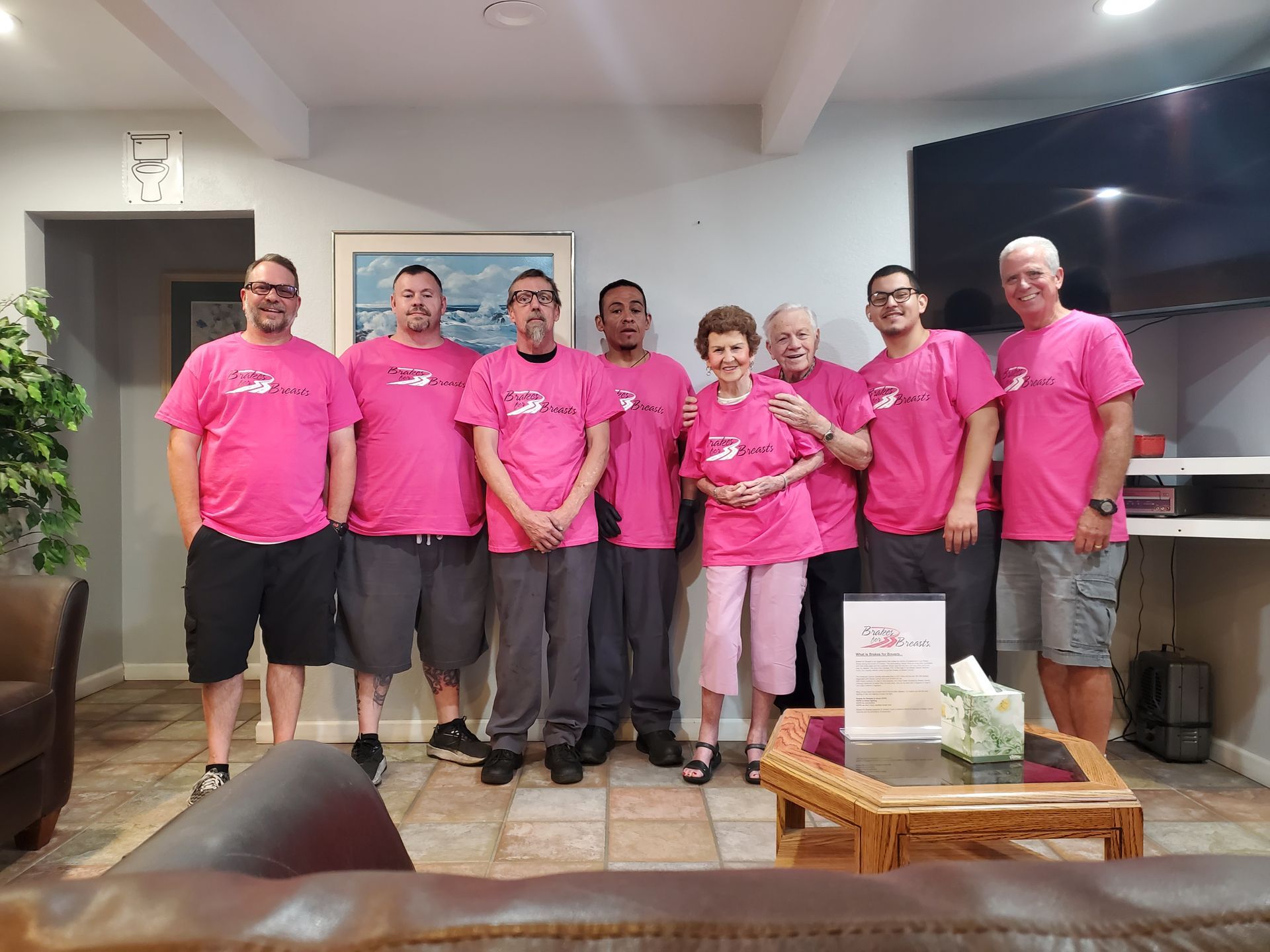 Group of people in pink shirts posing indoors.