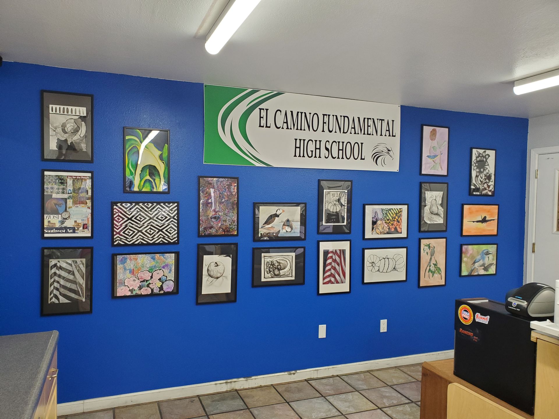 A blue wall displays framed artwork and a school banner, 