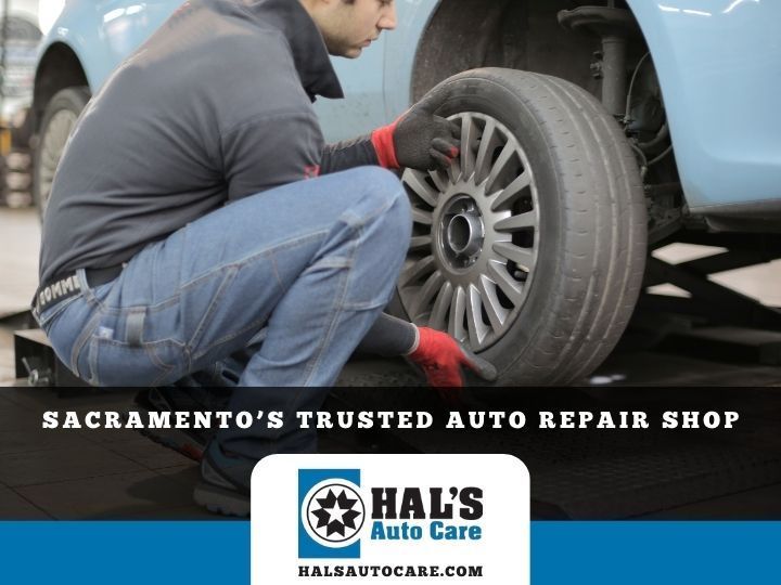 Mechanic changing a tire on a blue car. 