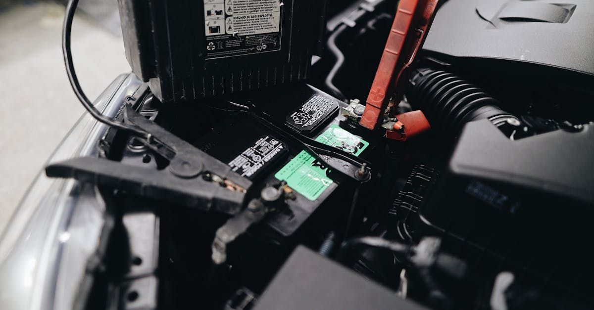 Car battery being jump-started; red and black cables attached to terminals in an open engine compartment.