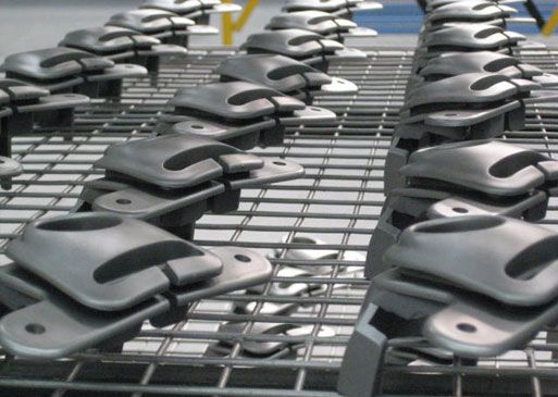 Rows of gray metal parts arranged on a metal grid, likely in a factory setting.