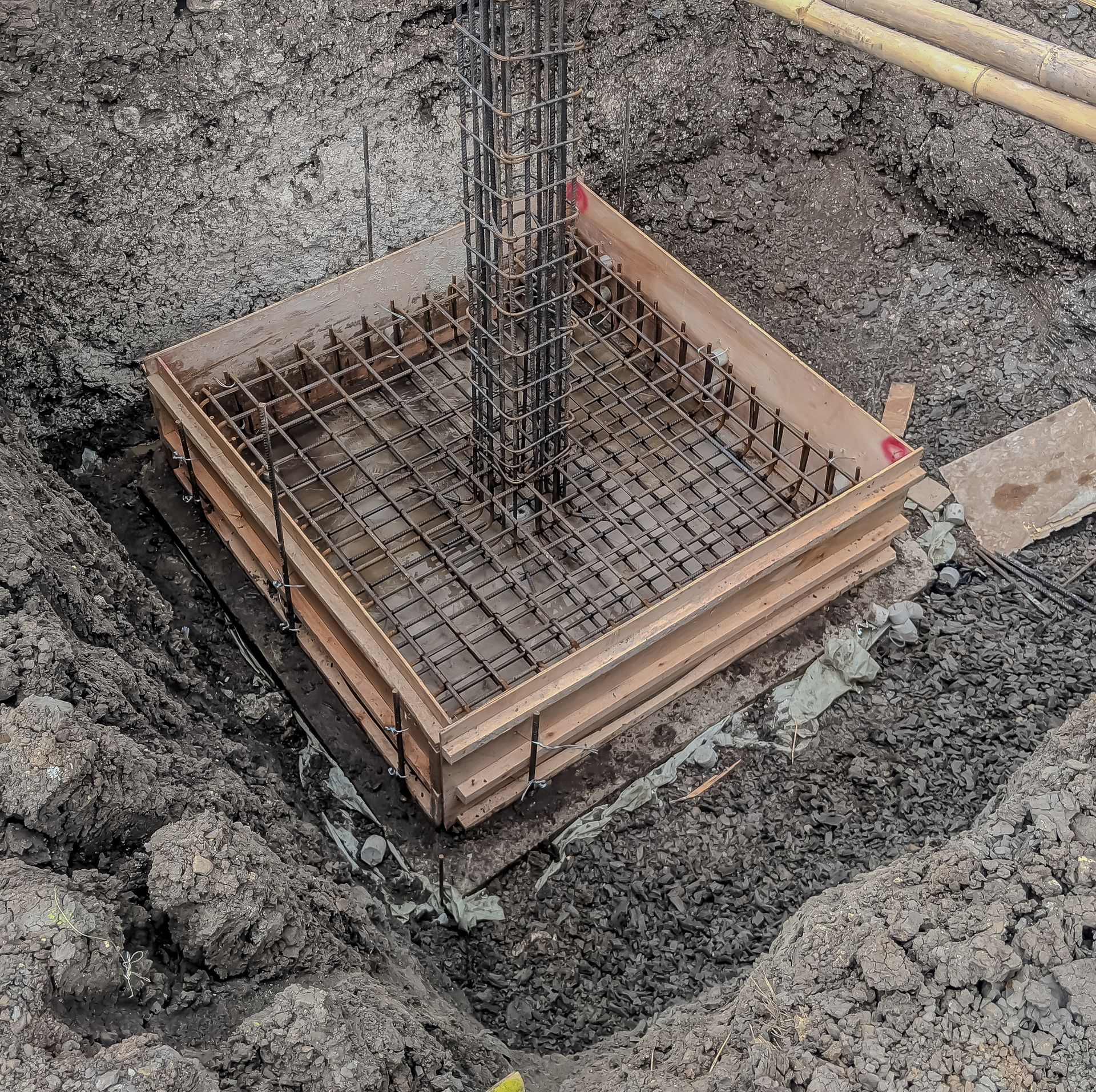 Concrete foundation formwork with rebar in a square excavation.
