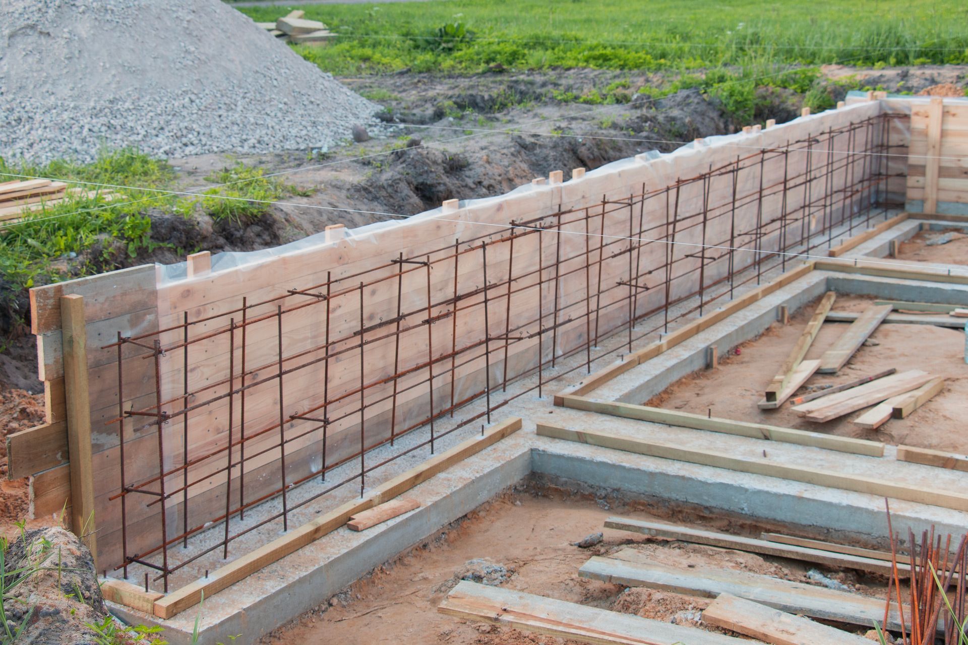 Wooden formwork with steel reinforcement bars set up for a concrete foundation at a construction site.