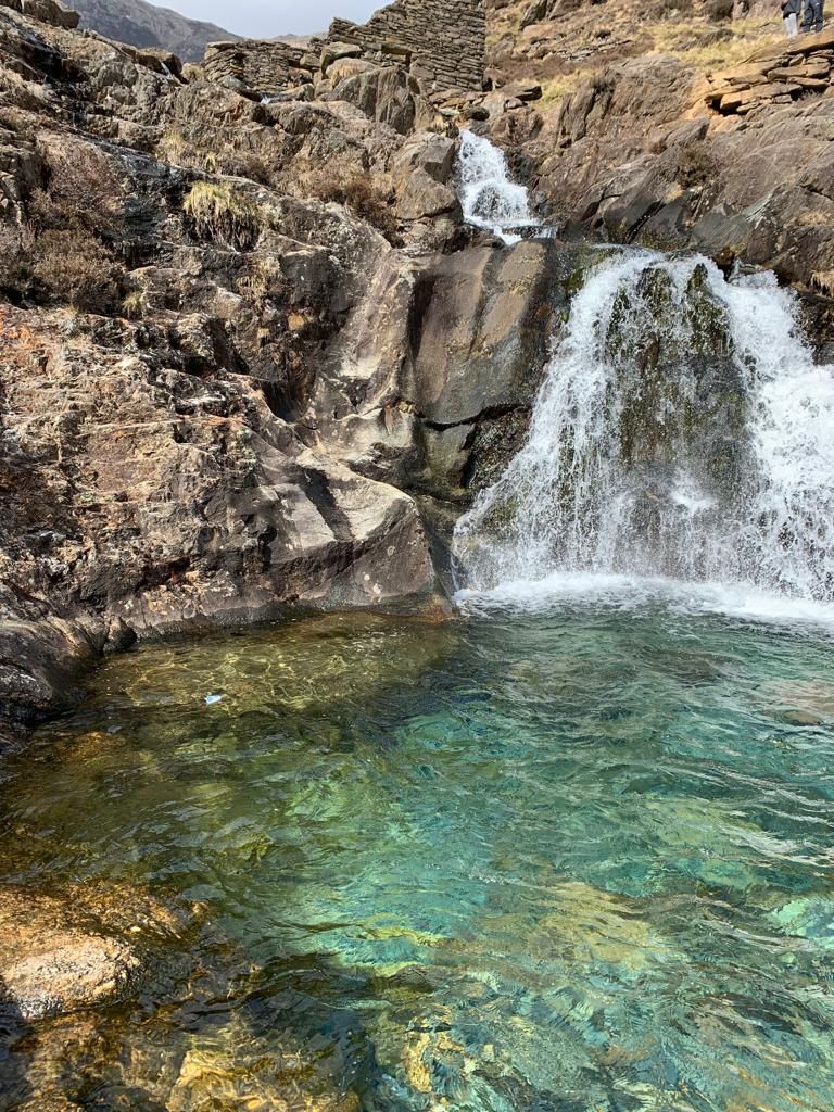 A waterfall is surrounded by rocks and a pool of water.