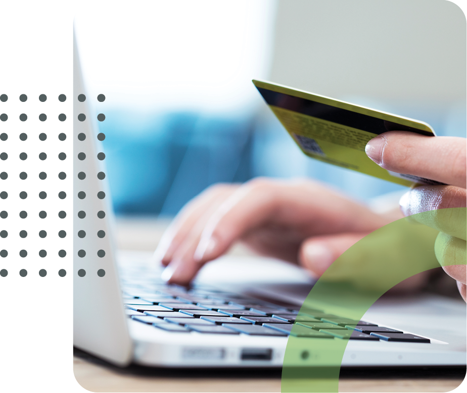 Person holding a credit card while typing on a laptop, suggesting an online purchase.
