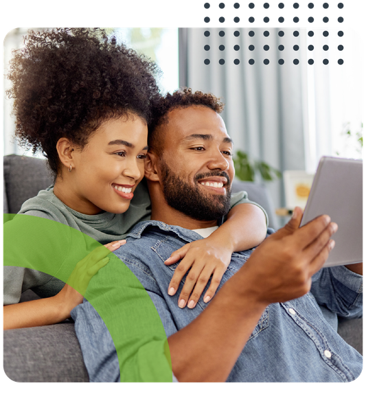 A man and a woman are sitting on a couch looking at a tablet.