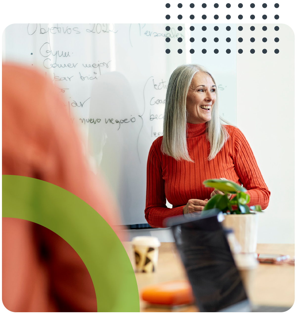 A woman is sitting at a table in front of a whiteboard.