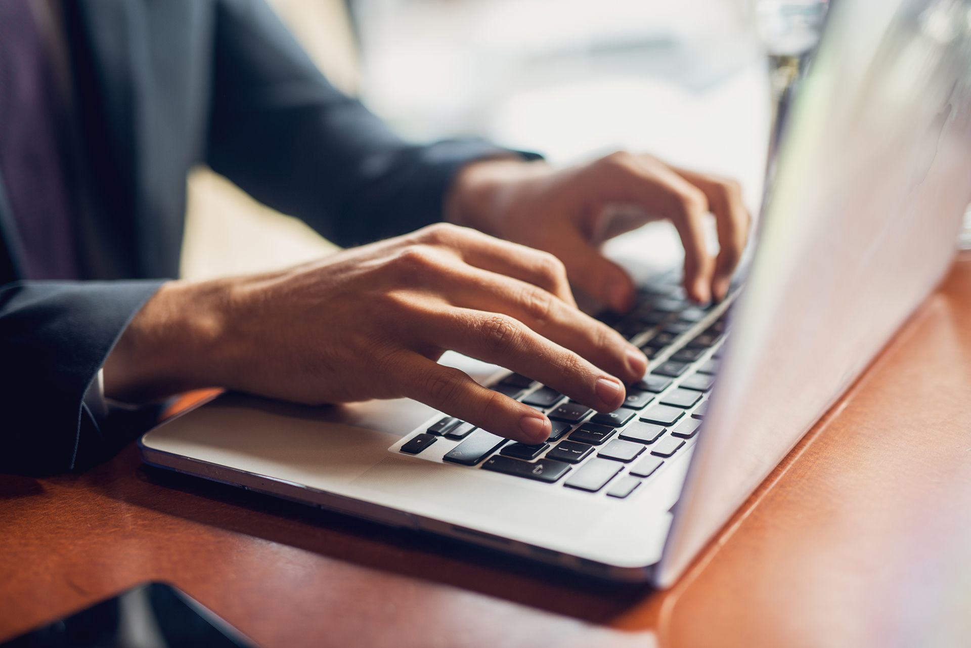 A man in a suit is typing on a laptop computer.