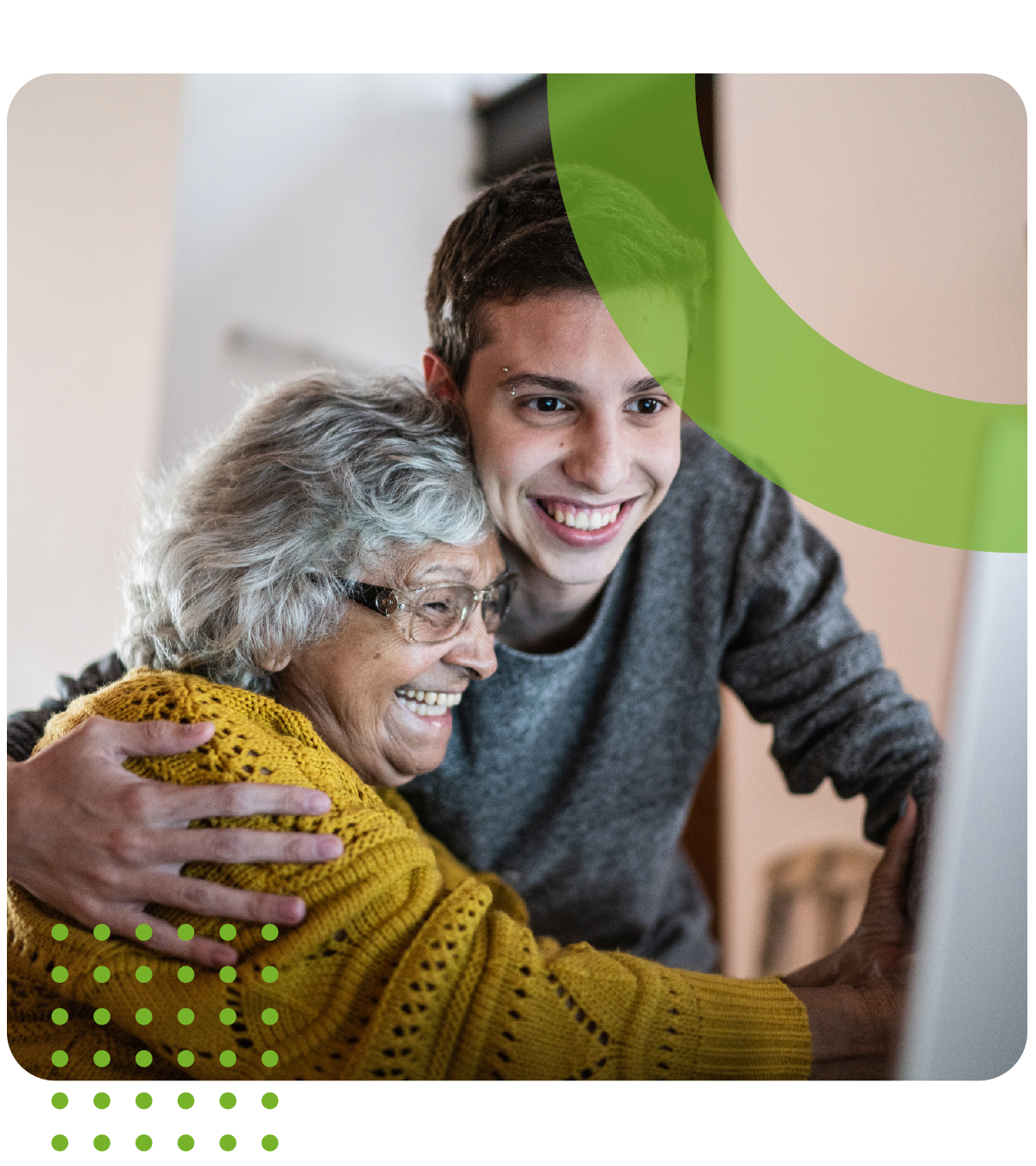 A young man is hugging an older woman while they look at a computer screen.