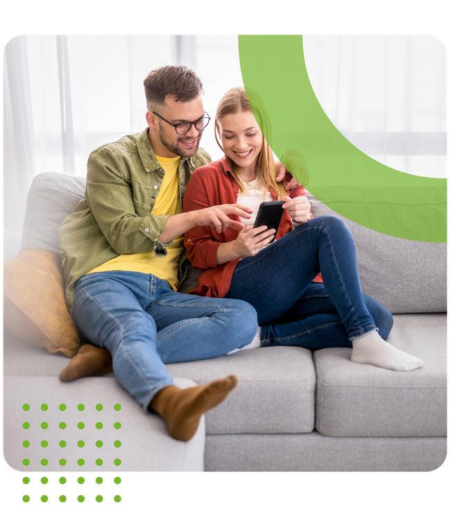 A man and a woman are sitting on a couch looking at a cell phone.