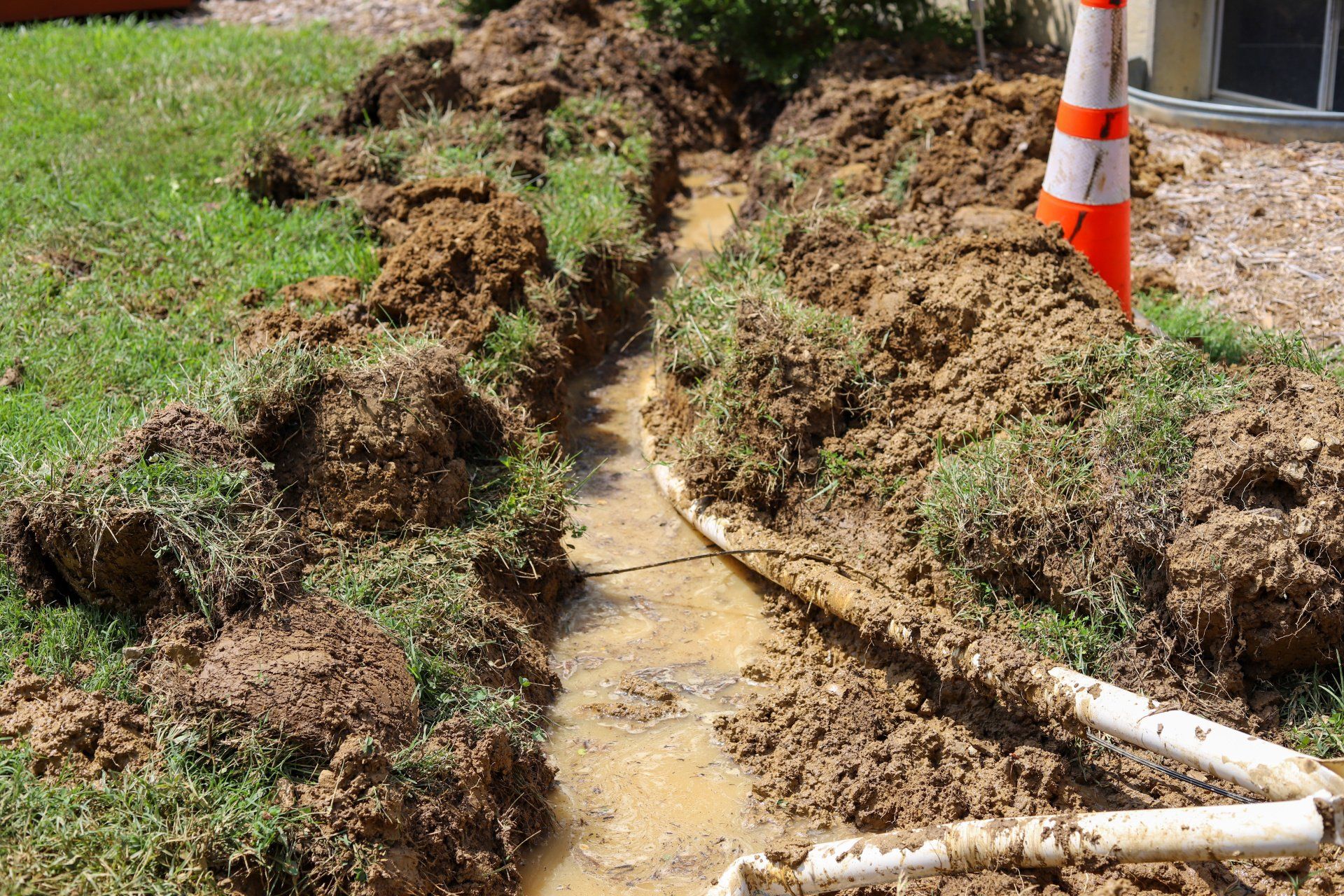 Broken sump pump PVC pile partially buried in the ground.