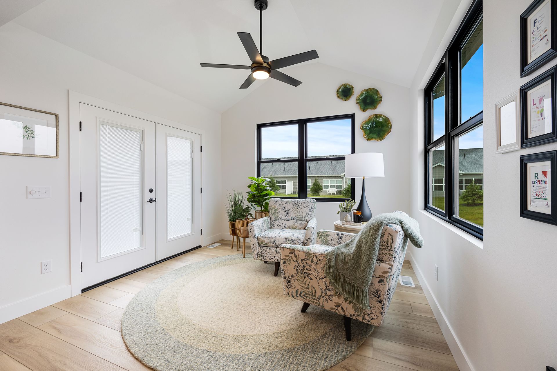 A living room with a ceiling fan , chairs , and a rug.