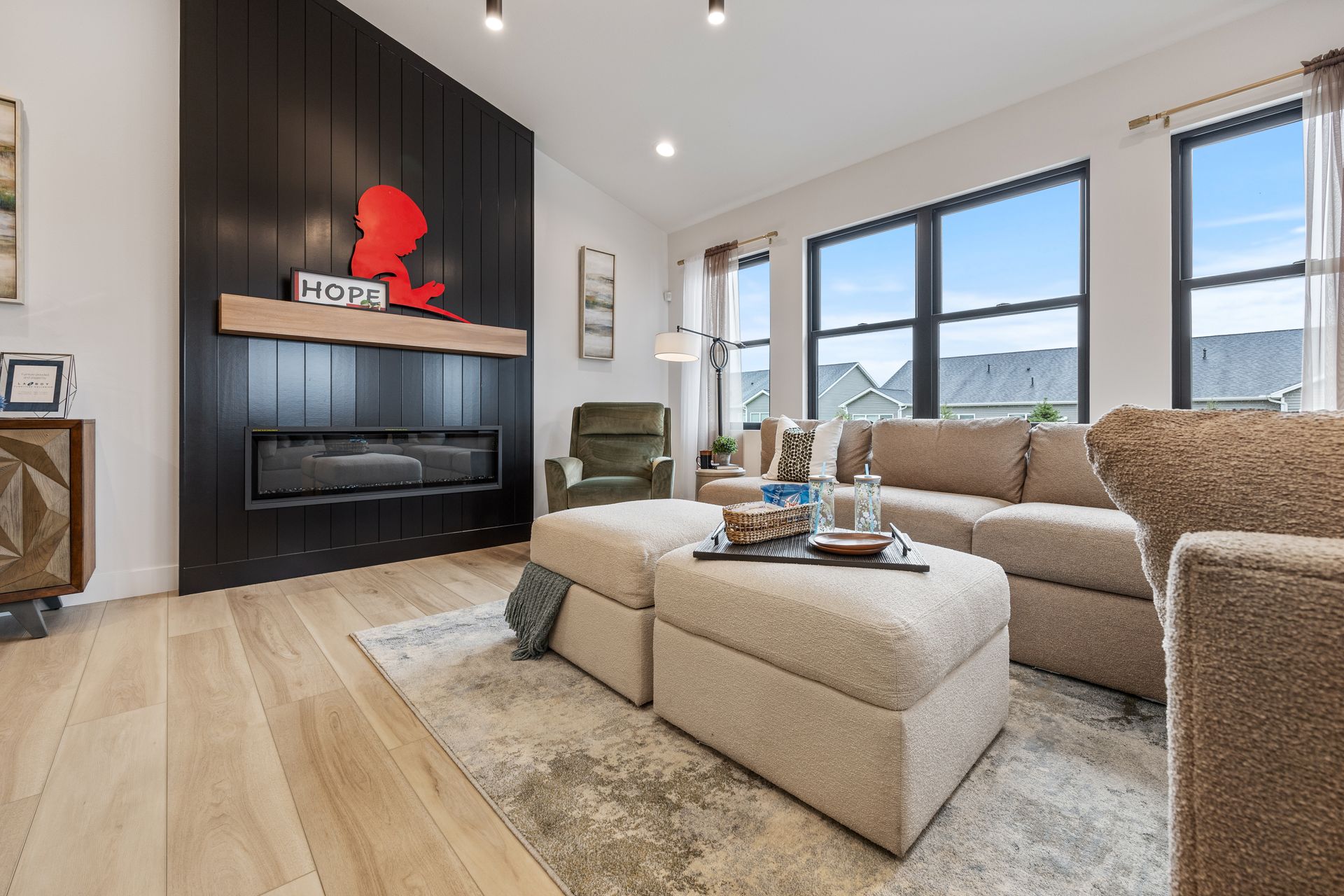 A living room with a fireplace , couch , chairs and ottoman.