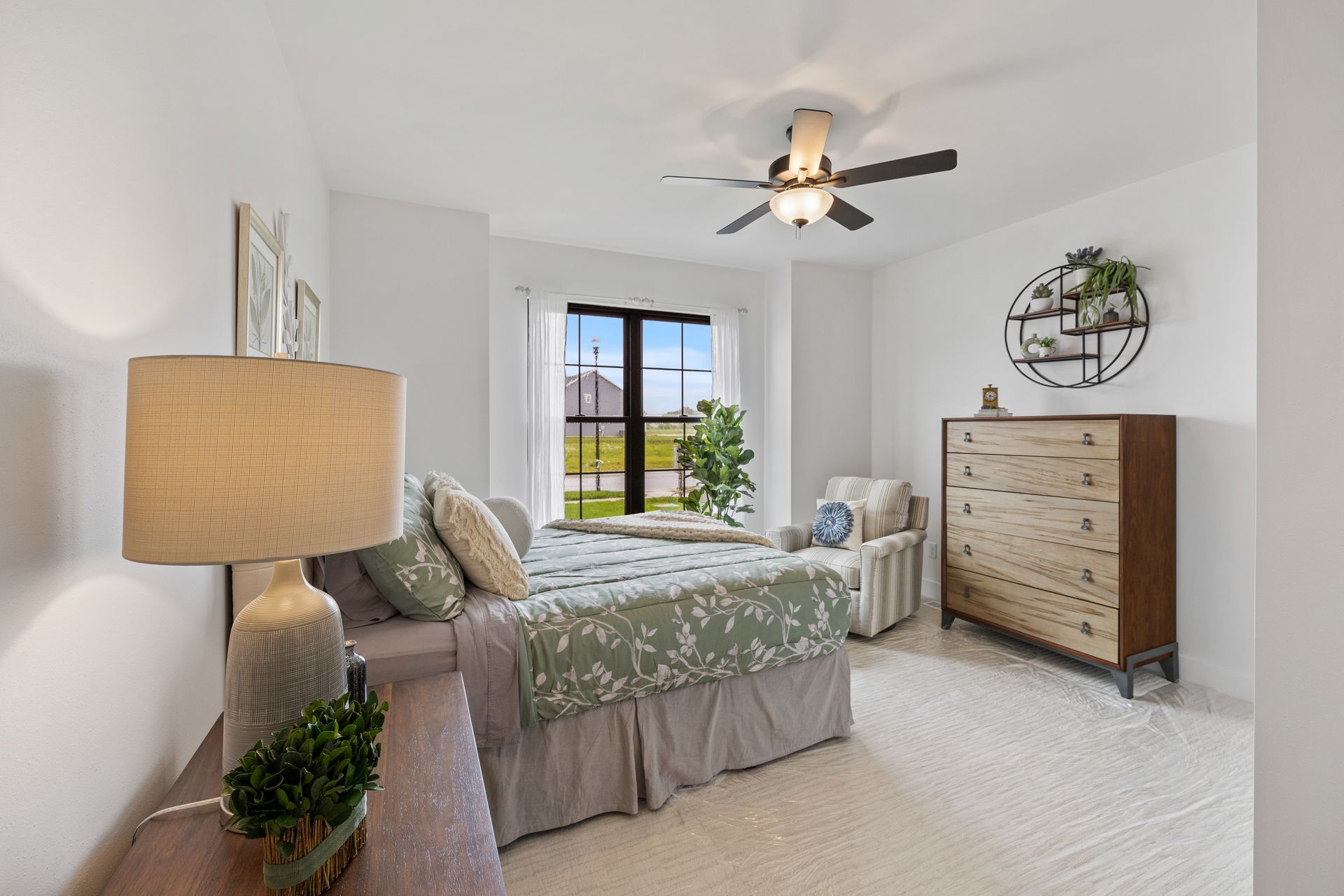 A bedroom with a bed , dresser , lamp and ceiling fan.