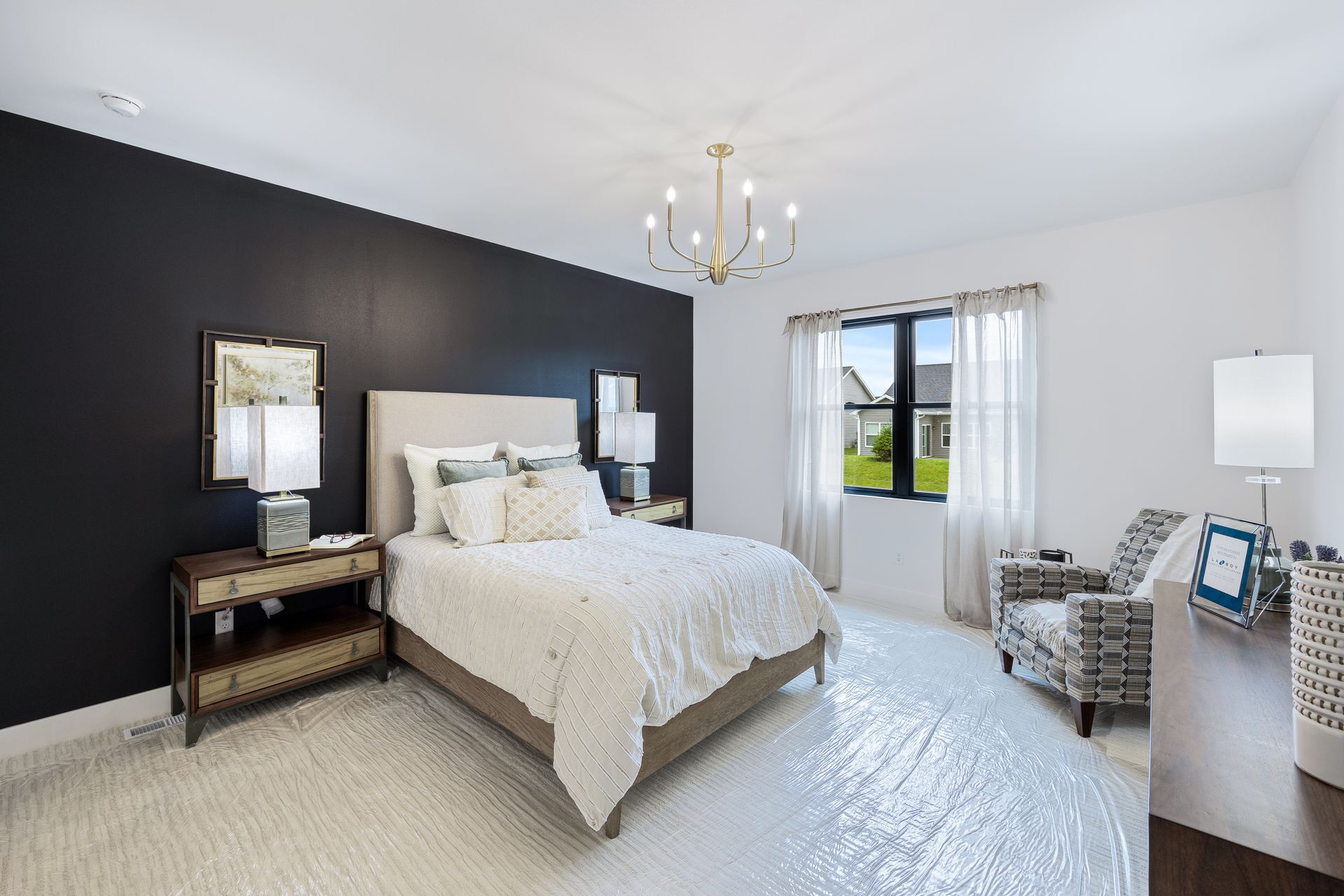 A bedroom with a bed , chair , nightstand , and chandelier.