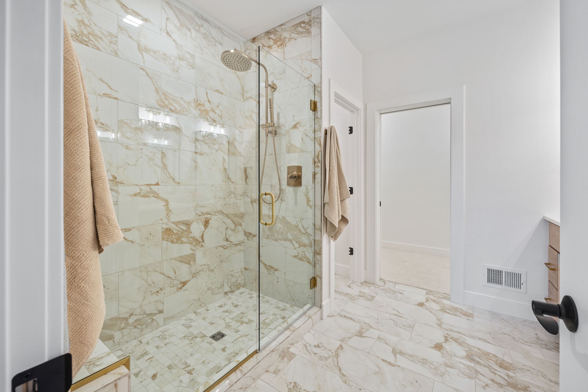 A bathroom with a walk in shower and a marble floor.