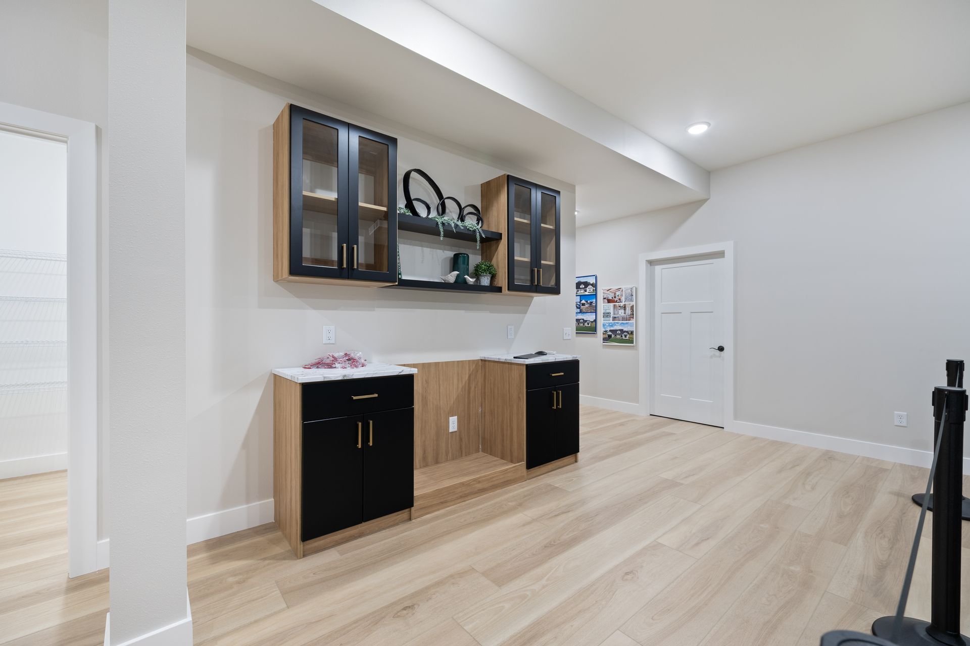 A basement with hardwood floors , cabinets and shelves.