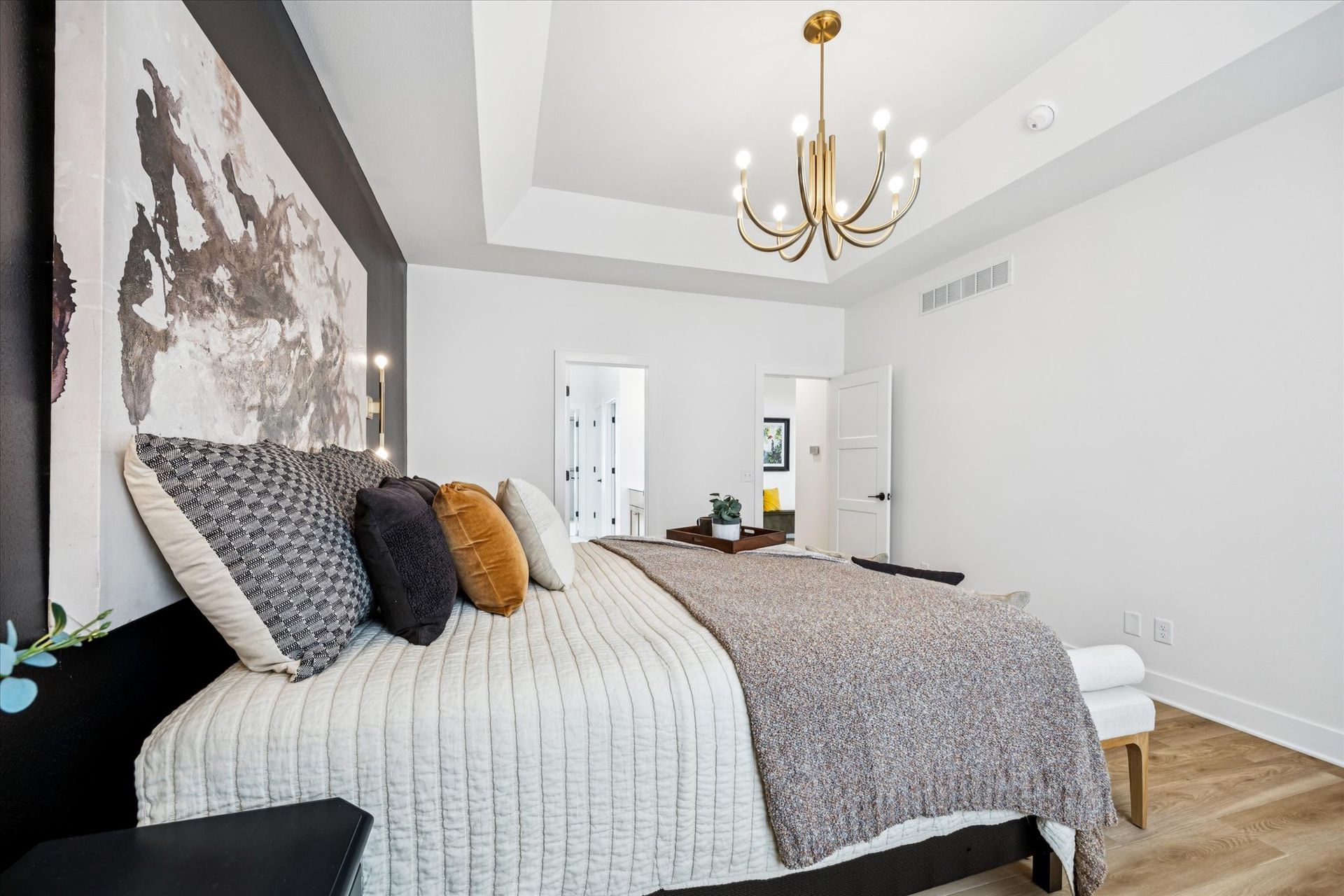 A bedroom with a large bed and a chandelier hanging from the ceiling.