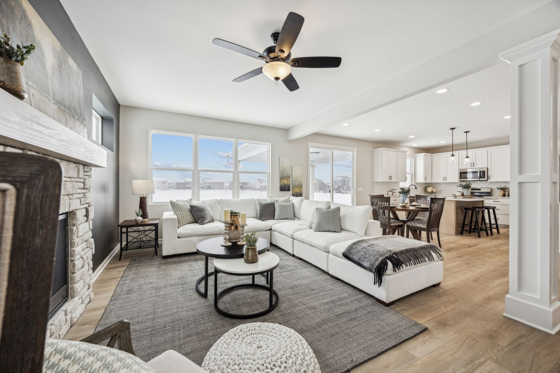Open-concept living space with white sectional sofa, fireplace, and kitchen in the background.