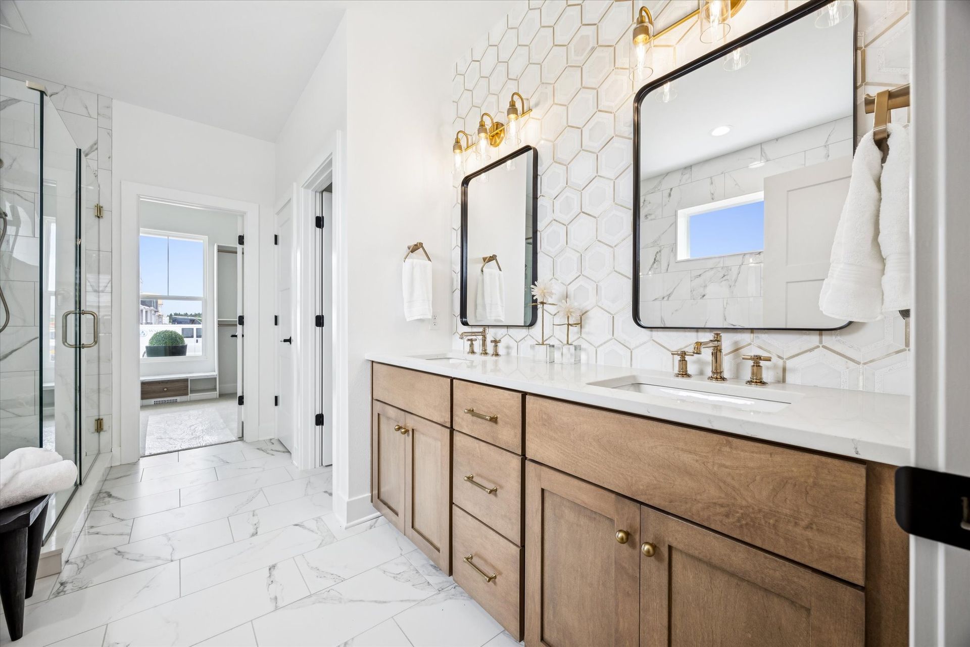 A bathroom with two sinks , two mirrors , and a walk in shower.