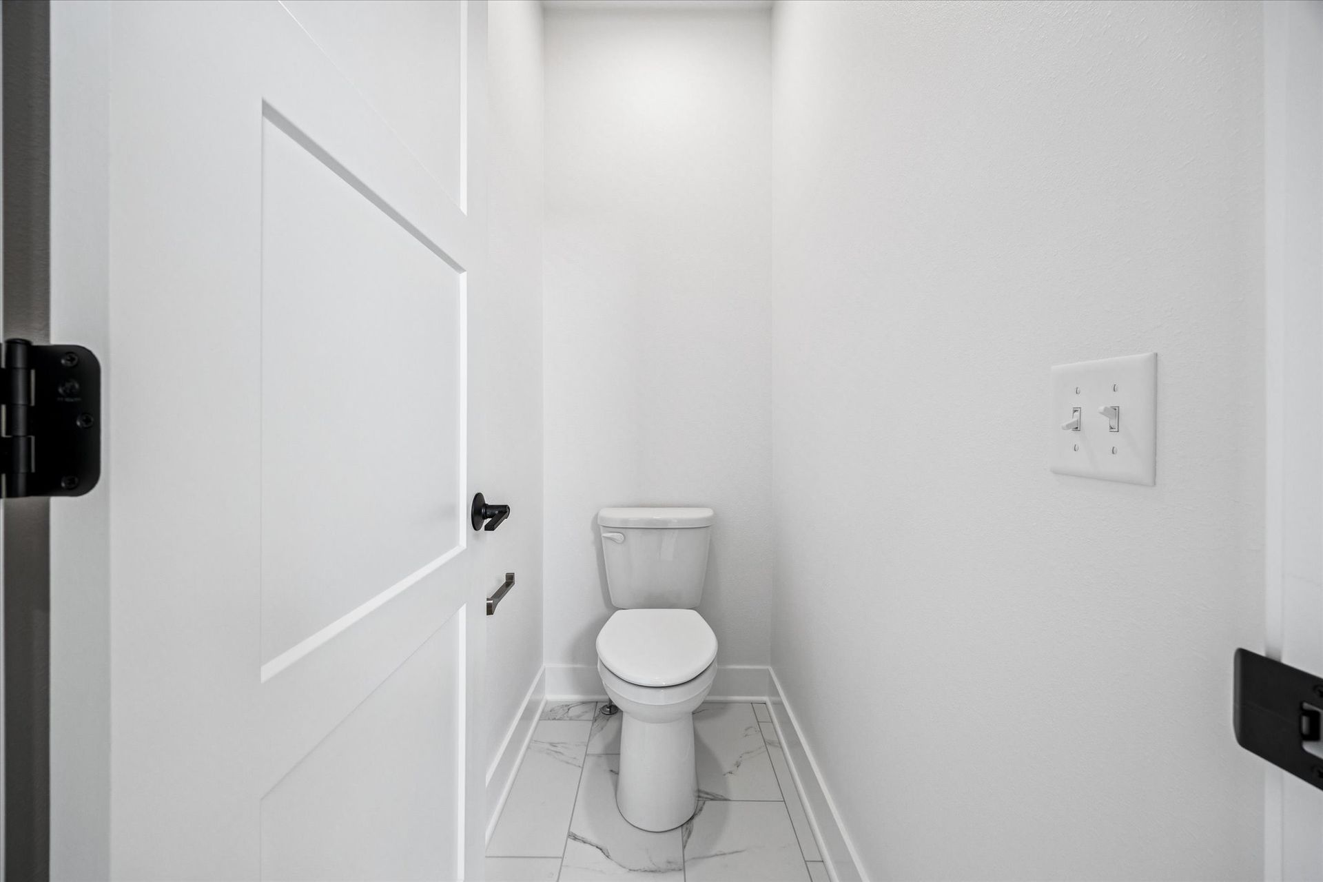A toilet is sitting in a small bathroom next to a door.
