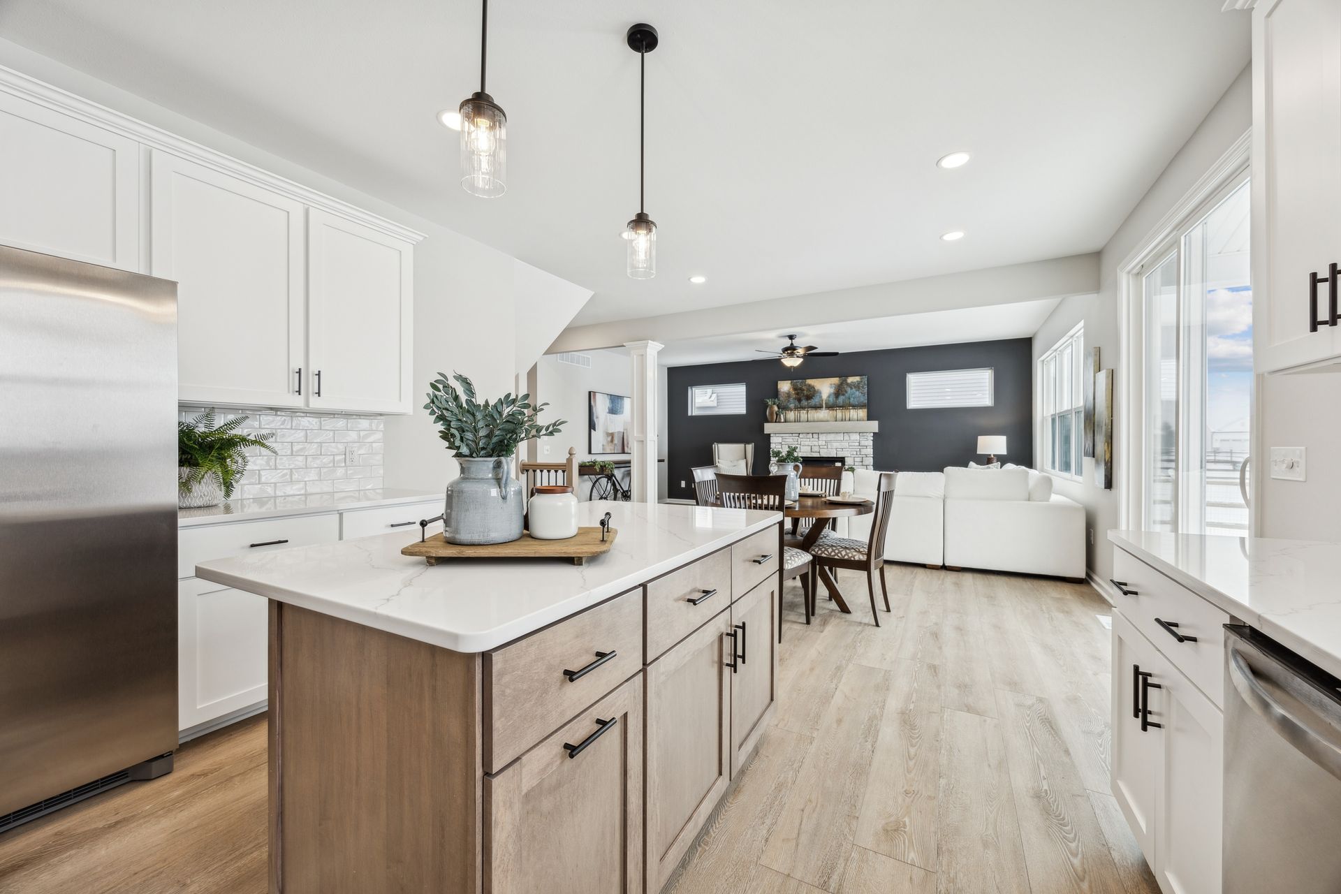 Modern kitchen with white cabinets, wood island, and open to living area with dark wall and fireplace.