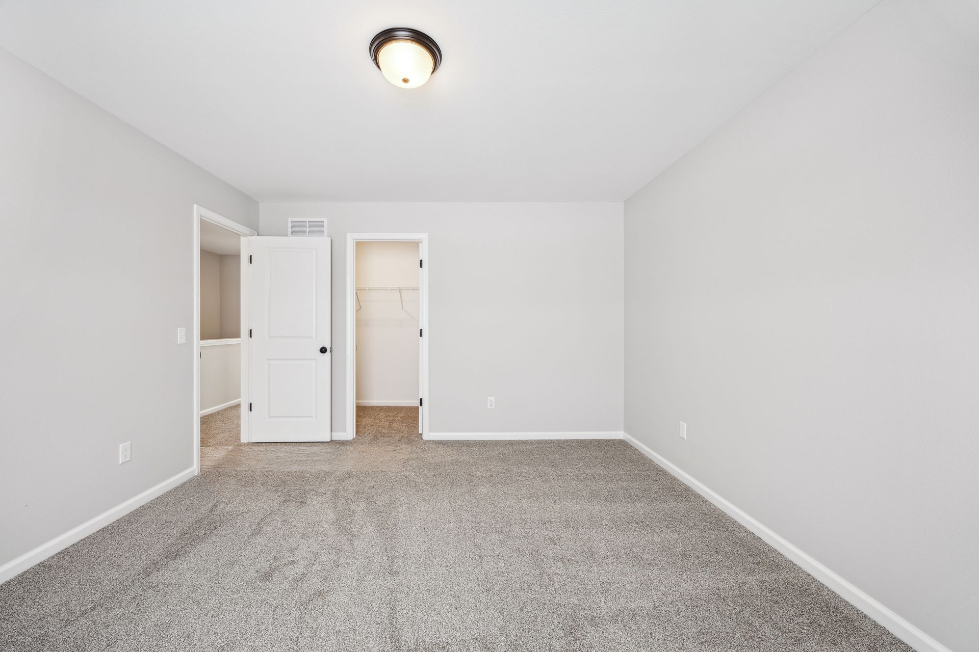 Empty bedroom with gray carpet, white walls, and a closet.