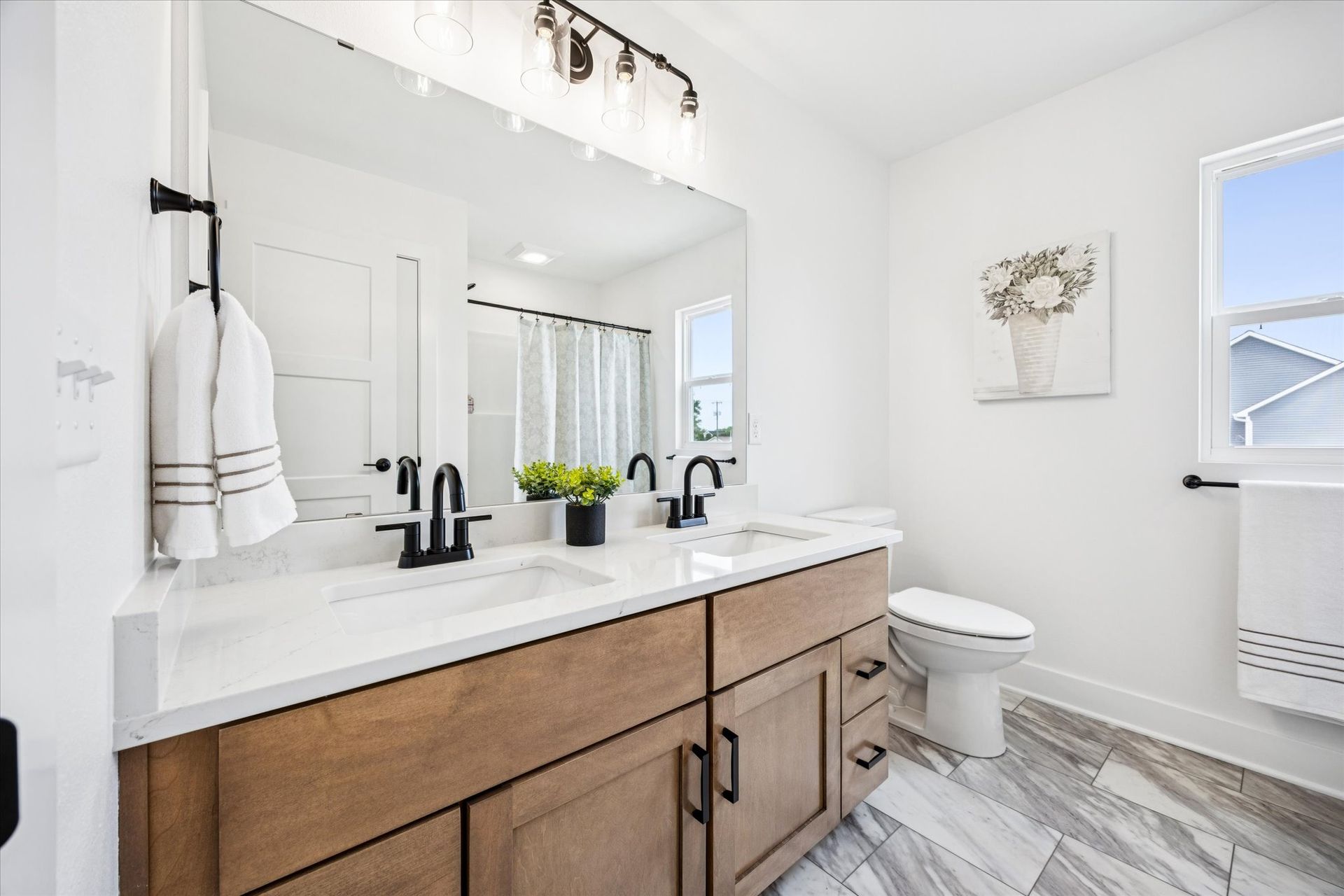 A bathroom with two sinks , a toilet , and a large mirror.