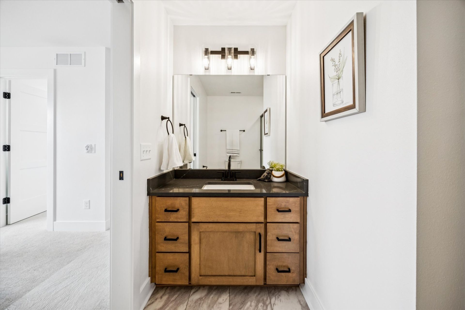 A bathroom with a sink , mirror and drawers.