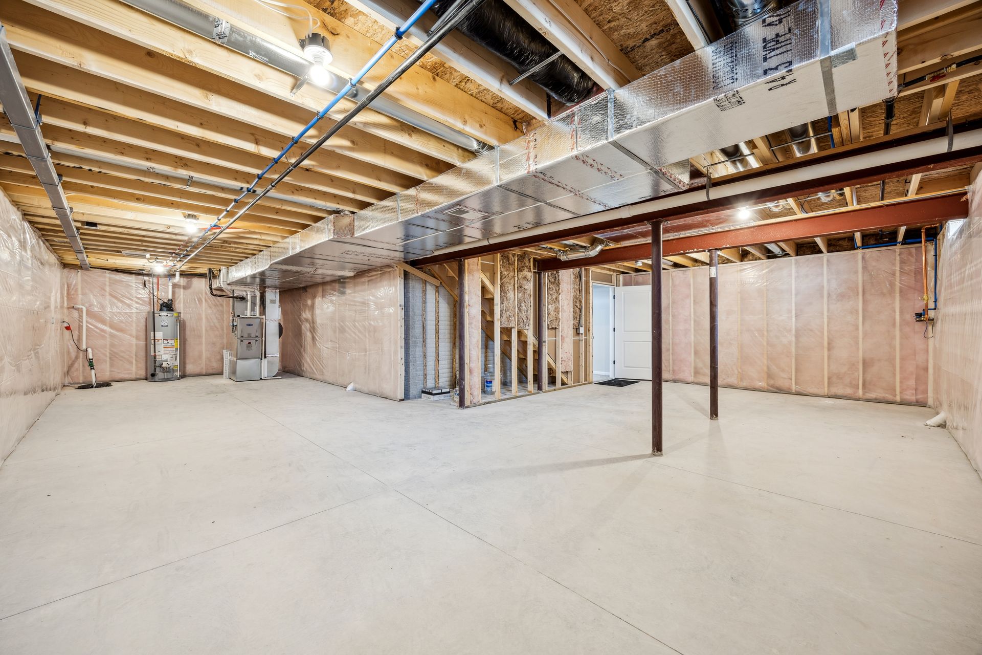 Unfinished basement with concrete floor, exposed beams, and insulated walls.