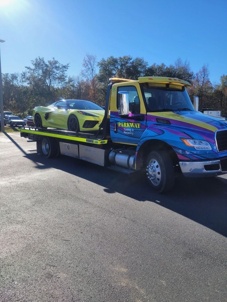 Colorful tow truck carrying a lime green sports car on a sunny road.