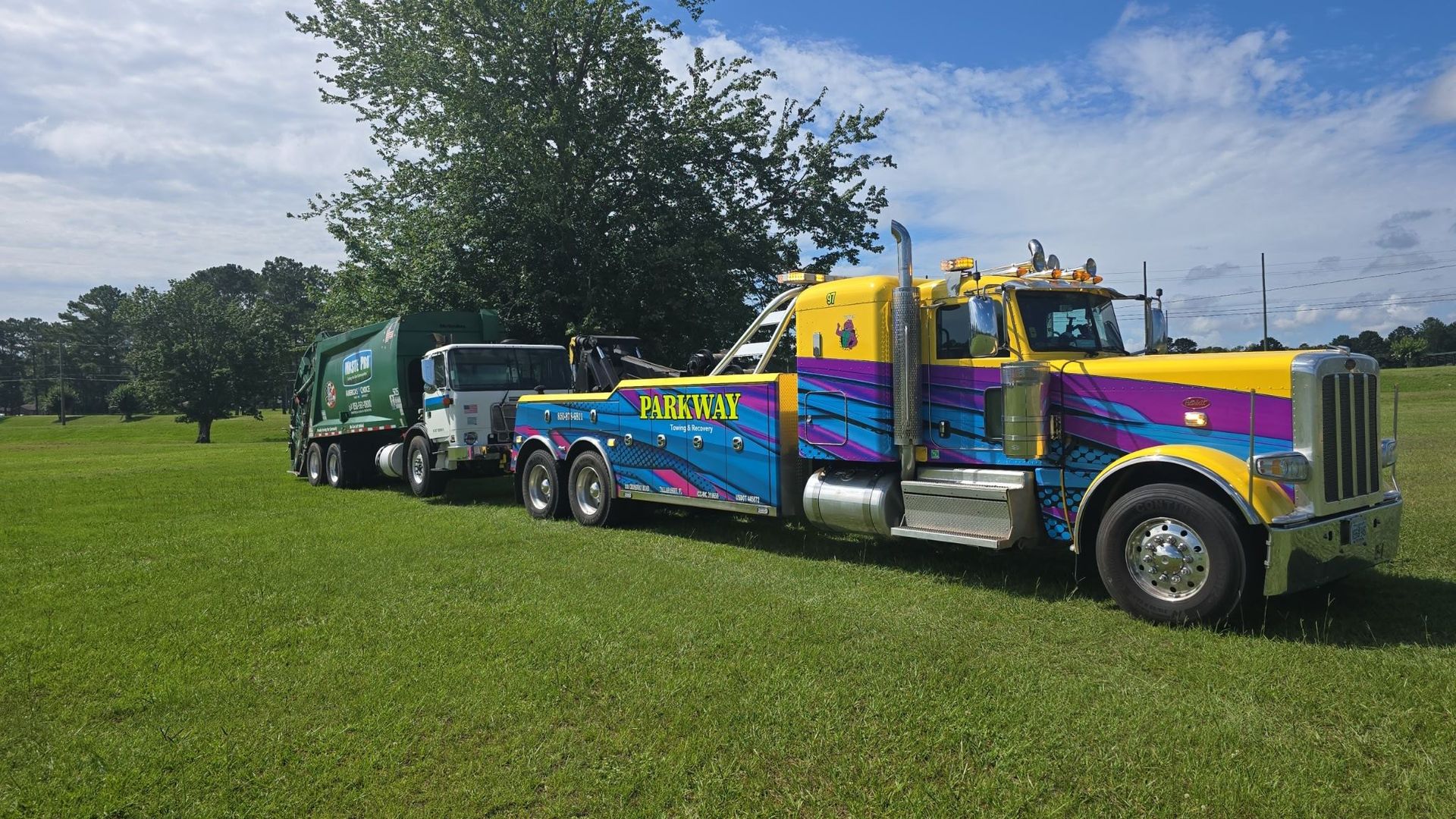 Yellow flatbed tow truck parked outside Parkway Wrecker Inc.