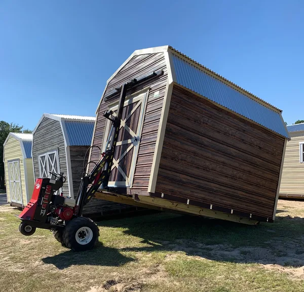 White prefab shed with double doors and windows on a grassy lot