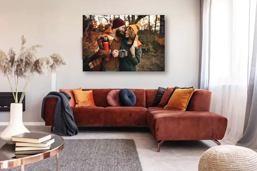 Un salon avec un canapé rouge et un grand tableau sur le mur.