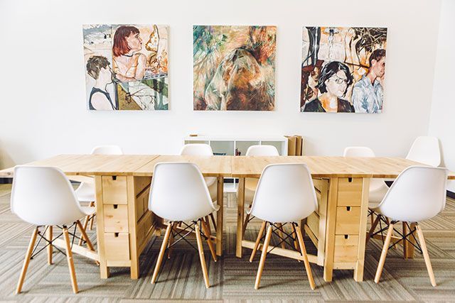 Il y a trois tableaux sur le mur au dessus de la table et des chaises.